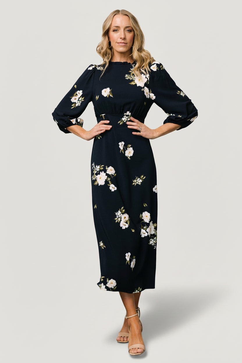 Front view of Karalie maxi dress in navy with ivory floral print, ruffled mock neck and smocked back waist, full-length view.