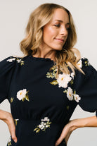 Rear detail of Karalie maxi dress showing smocked back waist, button-and-keyhole closure, and flowing skirt in navy floral.