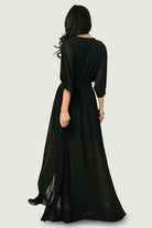 Side view of Kia Kimono Maxi Dress in black with left-side leg slit visible and skirt movement while standing.