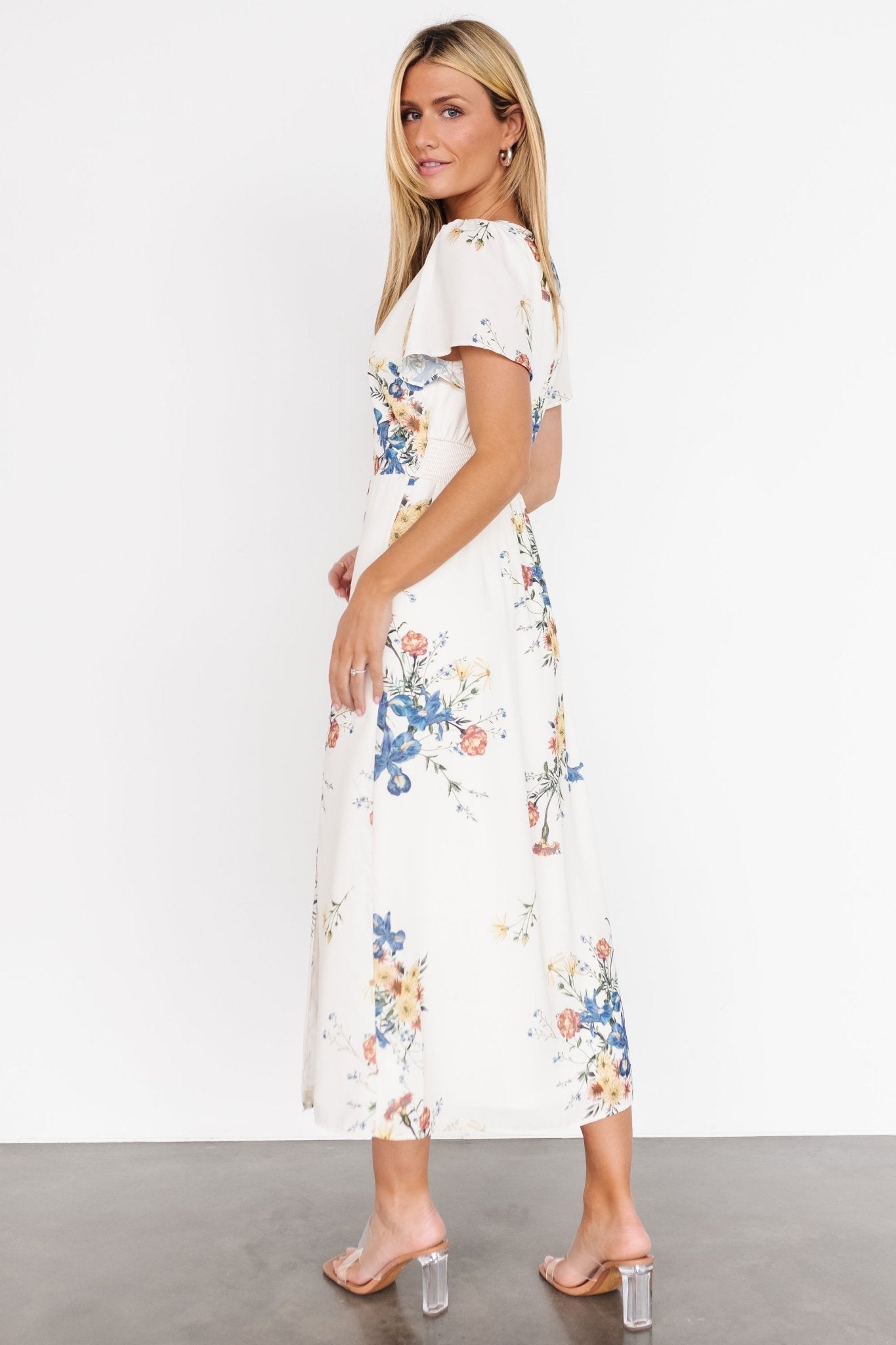 Styled look of the Kirsten Midi Dress in cream floral paired with neutral sandals, showing versatile daytime to evening wear potential.