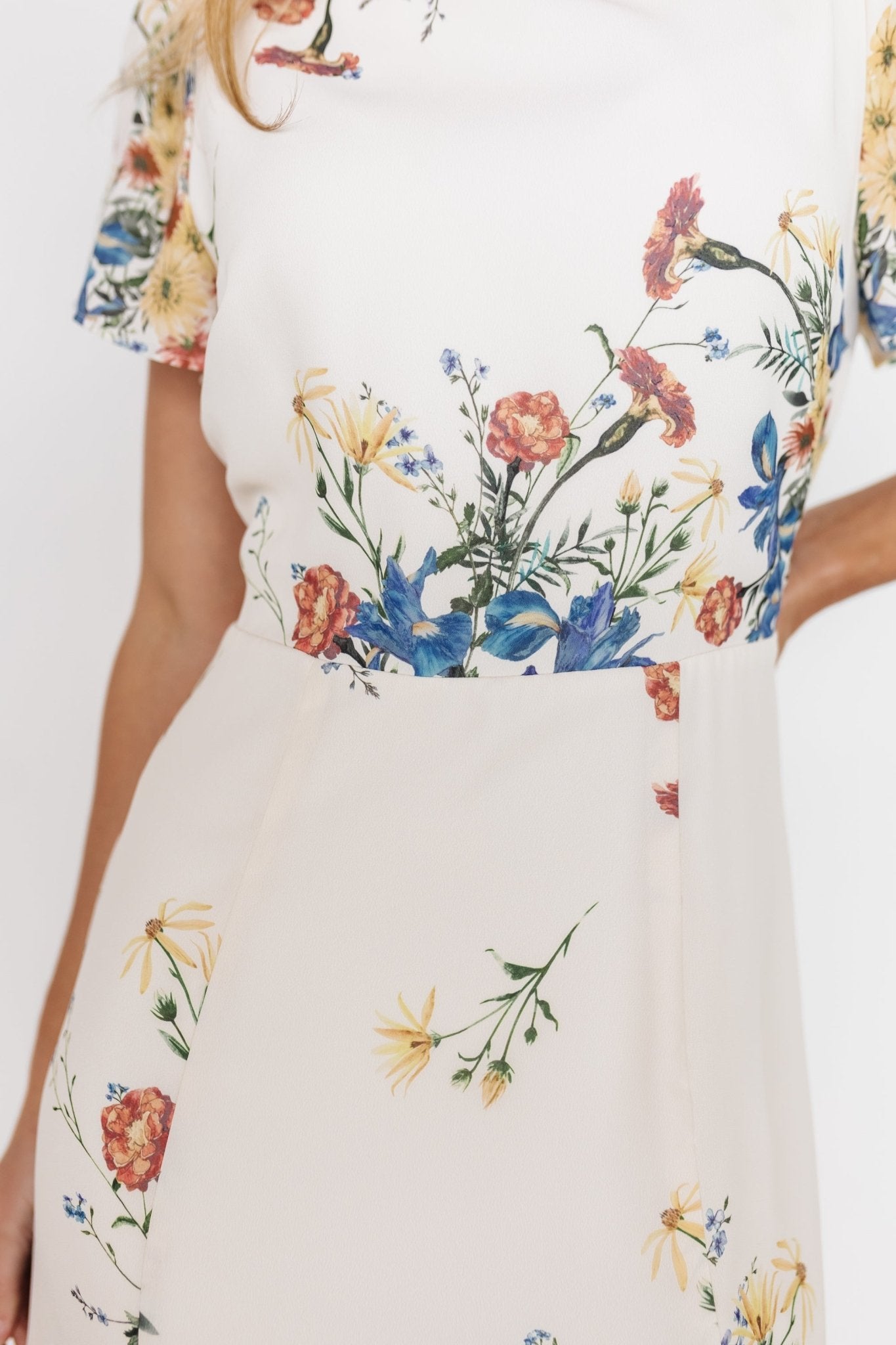 Model movement shot in the Kirsten Midi Dress cream floral, illustrating flowy chiffon skirt, left slit, and comfortable fit for events.