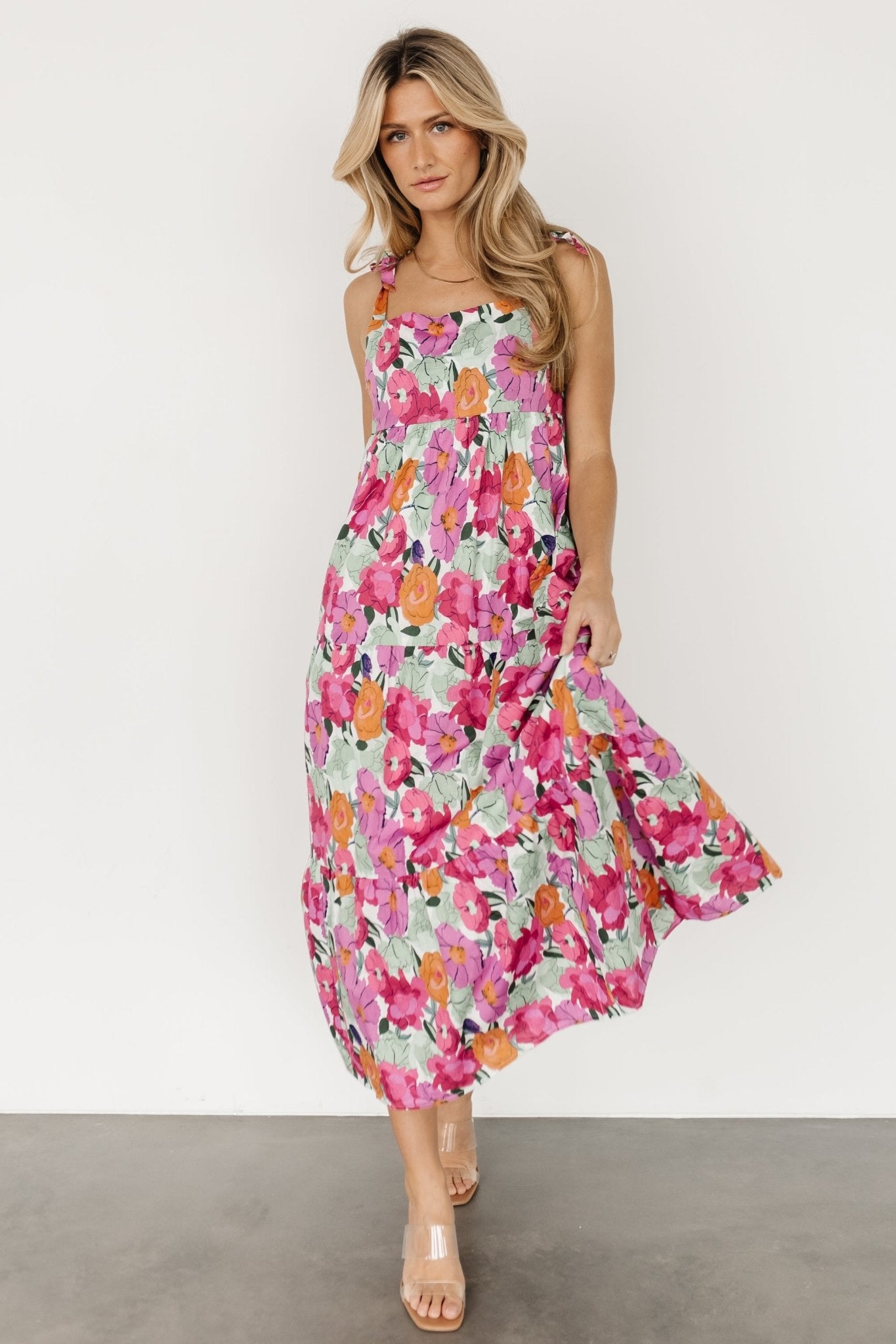 Three-quarter view of the floral midi dress highlighting the smocked back, short inner lining and natural drape of the cotton fabric.