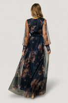 Full outfit shot of dark blue floral tulle maxi dress on model, showing length, silhouette, and smocked waist detail.