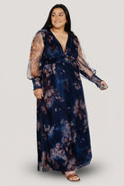 Close-up of deep V-neck and smocked waist on dark blue floral tulle maxi dress, highlighting fabric texture and print.