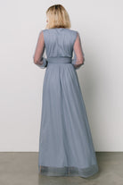 Studio shot of the whisper-blue Layla Tulle Maxi Dress on a mannequin showing deep V-neckline, smocked cuffs, and layered tulle skirt details.