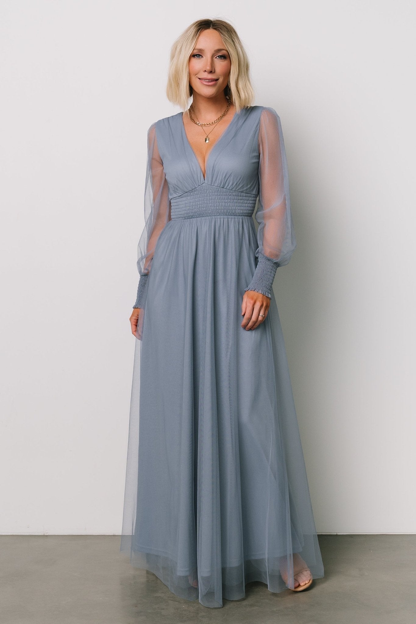 Three-quarter shot of the whisper-blue Layla Tulle Maxi Dress highlighting sheer long sleeves with smocked cuffs and the dress’s layered tulle texture.