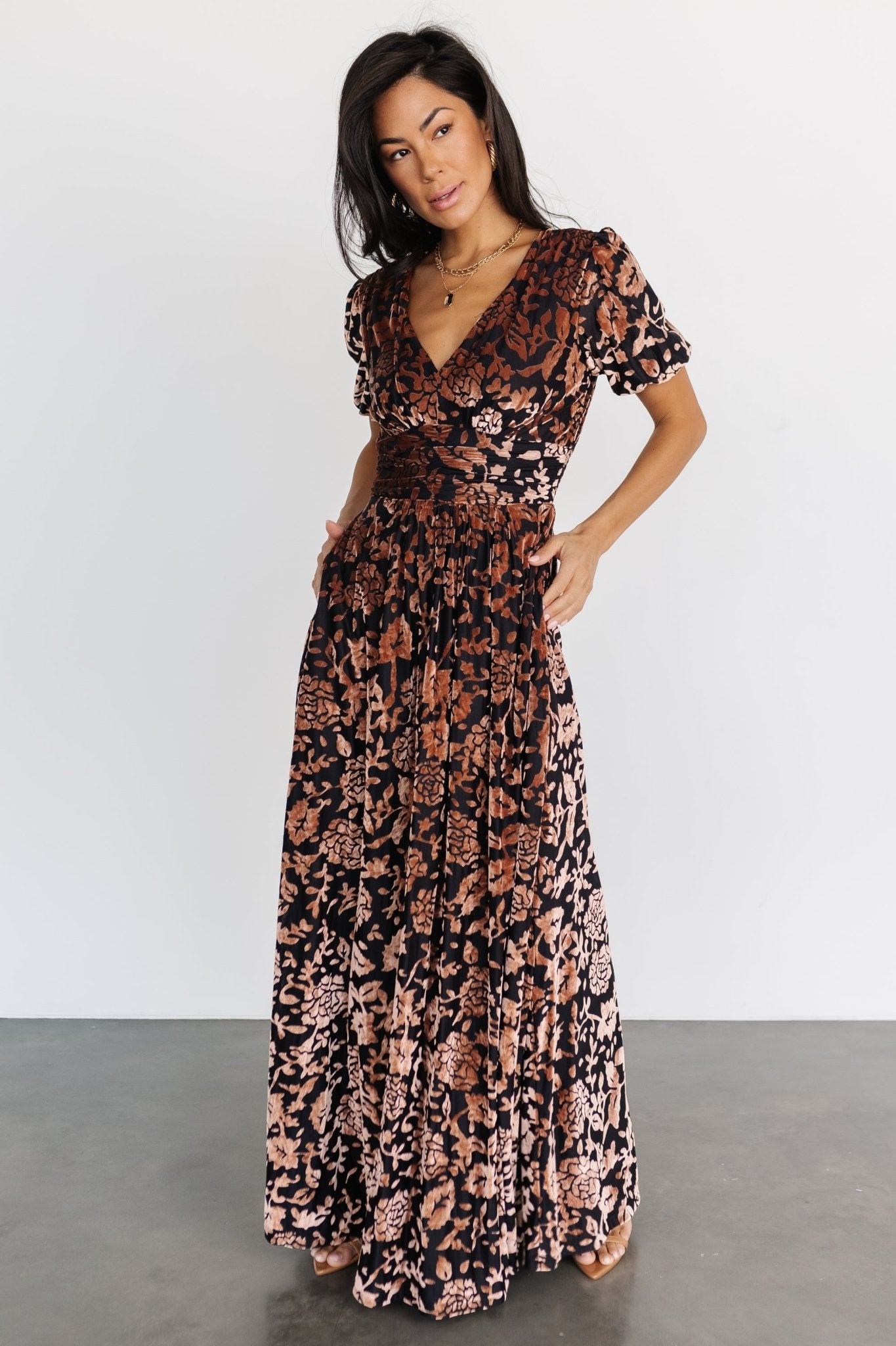 Full-length studio image of Leslie embossed velvet maxi dress in Black + Bronze, highlighting V-neck, gathered waist, and soft skirt movement.