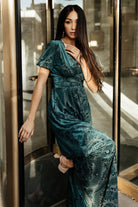 Full-length studio image of the Leslie emerald velvet maxi on a model, presenting silhouette, length, and polished finish.