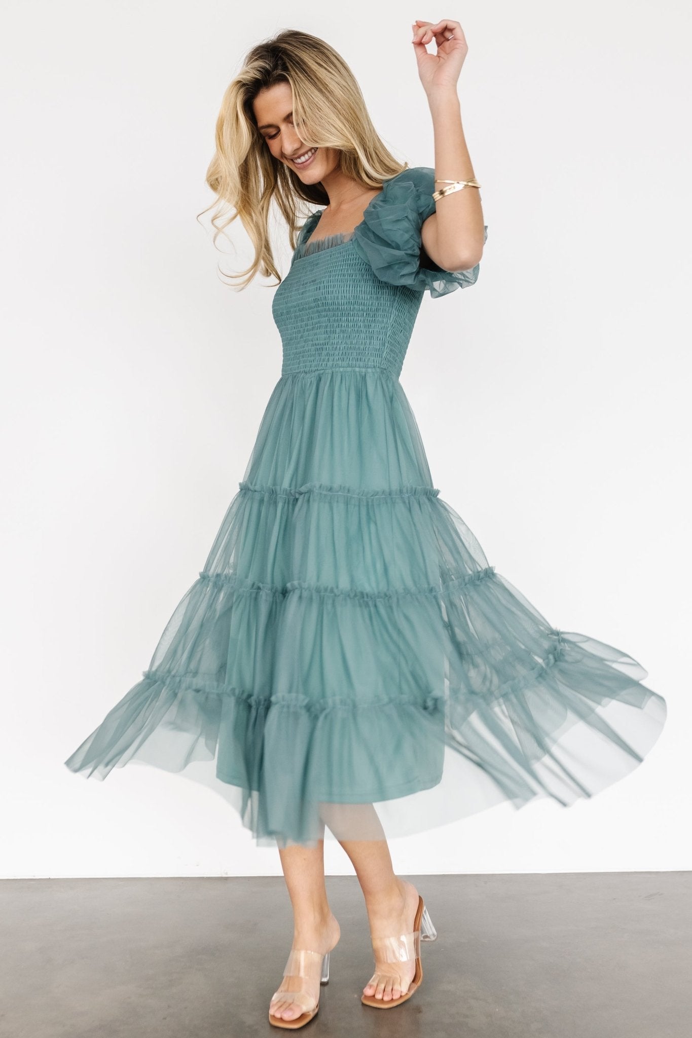 Side view of eucalyptus tulle midi dress in motion, emphasizing tiered skirt movement, puff sleeve detail, and overall midi length.