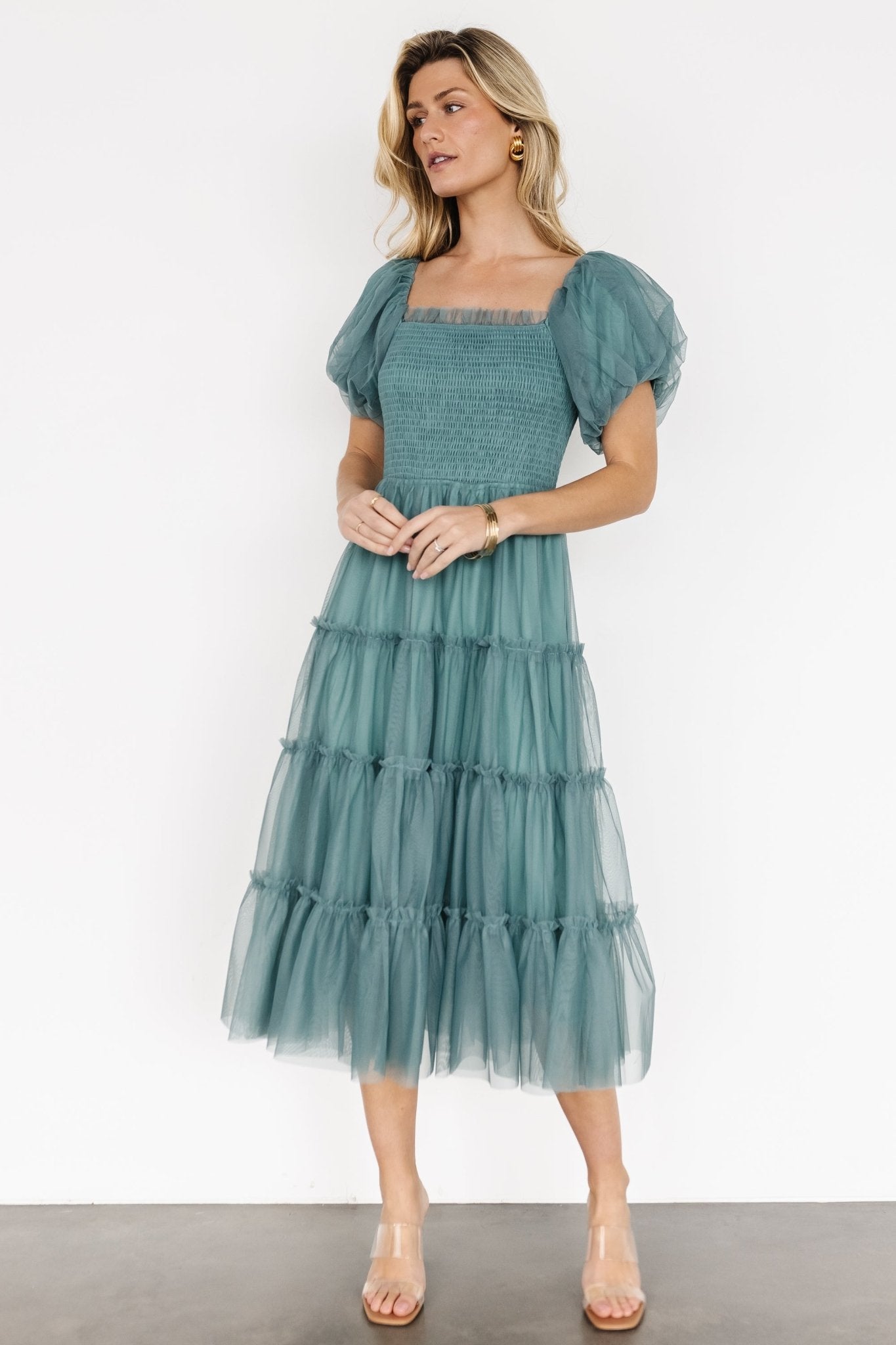 Front view of eucalyptus tulle midi dress on model showing smocked stretch bodice, ruffle square neckline, lined puff sleeves and tiered skirt.