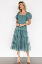 Front view of eucalyptus tulle midi dress on model showing smocked stretch bodice, ruffle square neckline, lined puff sleeves and tiered skirt.