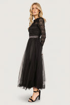 Studio image of the Lonnie Tulle Dress in black on a mannequin, showing overall silhouette with ruffled lace overlay and midi tulle skirt movement.