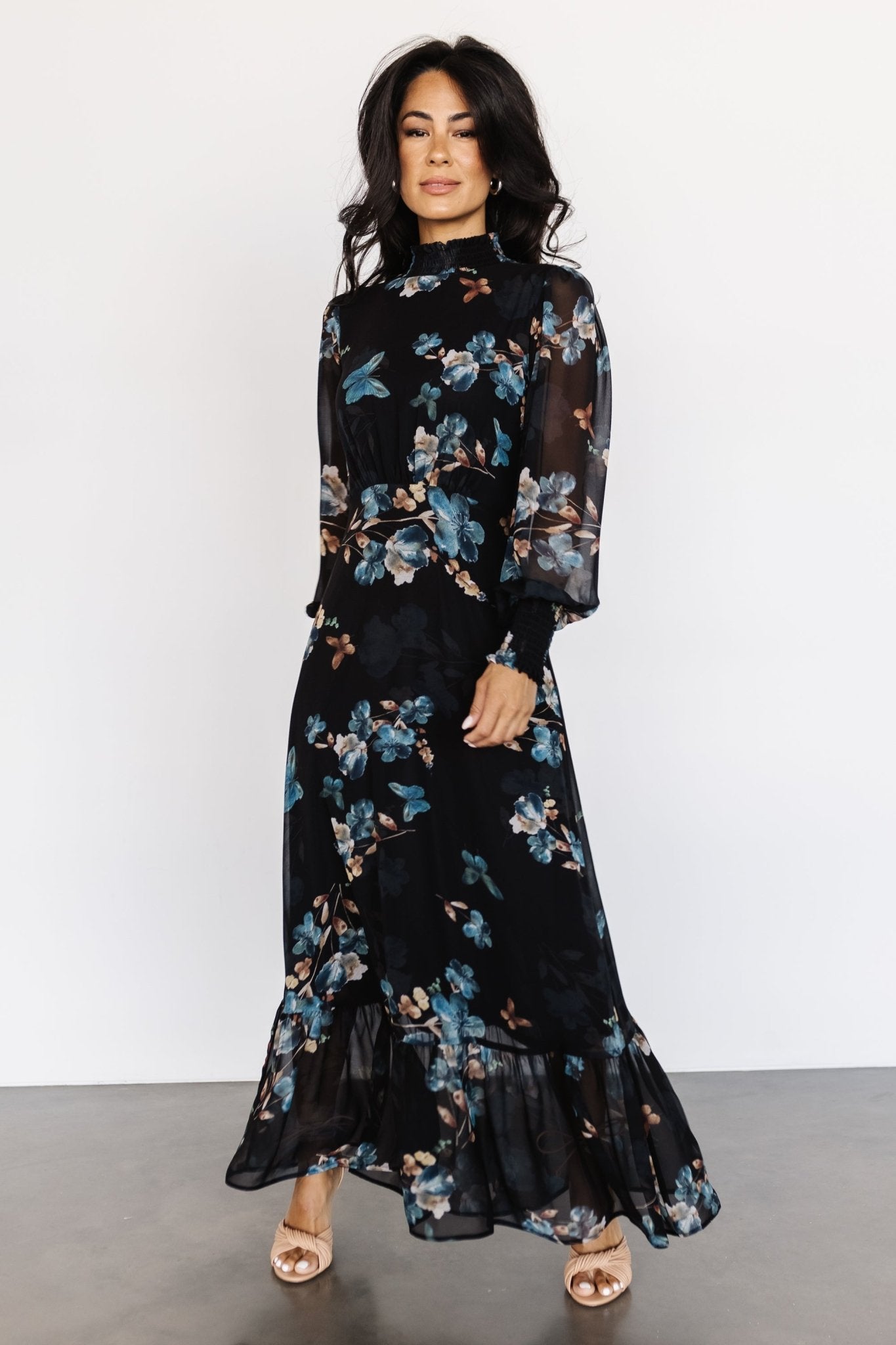 Three-quarter view of a black and blue chiffon maxi featuring smocked neckline, keyhole back with double-button closure, and flowing tiers.