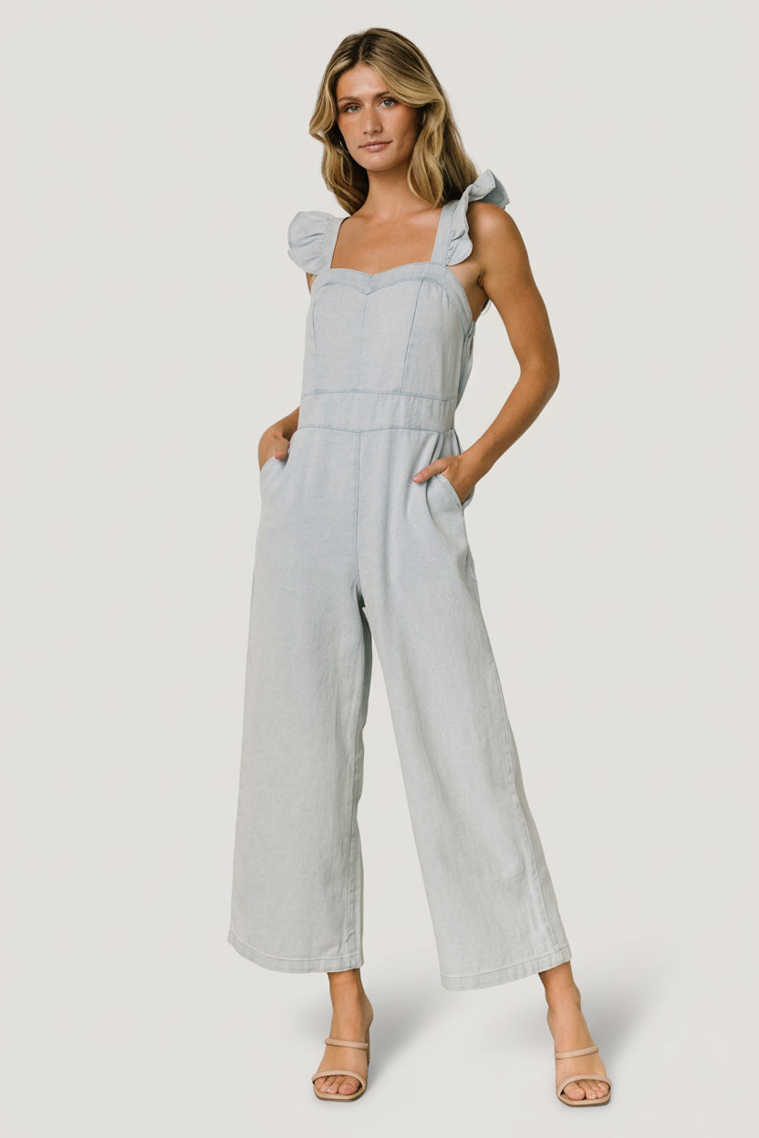 Front view of blue Madison denim jumpsuit showing sweetheart neckline, ruffle tank sleeves, elastic back, and wide pant legs.