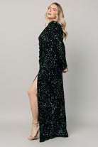 Back view of the emerald sequin maxi dress on model, showing hidden zipper, fitted bodice and full-length skirt silhouette.