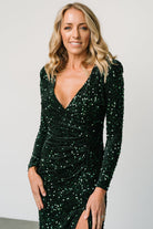 Detail shot of ruched left waist and front-left slit on emerald sequin maxi dress, illustrating construction and slit height.