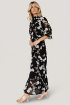 Detail image of pleated front waist and flowing chiffon tiers, illustrating skirt volume and soft drape in black with slate-blue florals.