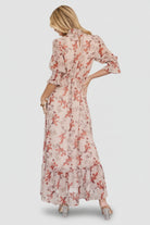 Close-up of smocked mock neckline and pleated front waist on blush floral chiffon fabric, showing texture and stitching details.