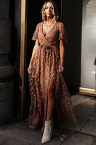 Model wearing the nude-rose embossed maxi dress, showing full length, elastic waist with tie, and flowing skirt silhouette.