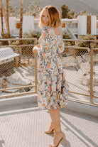 Full-length studio shot of the multi floral smocked midi dress on a model, highlighting tiered skirt and overall fit.