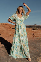 Three-quarter view of Maya Maxi Dress in Garden Multi on model, highlighting elastic shoulders, half sleeves with elastic cuffs, and flowing skirt.