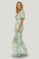 Full-length shot of model twirling in the Maya Maxi Dress, illustrating tiered maxi skirt movement and vibrant garden multi floral pattern.