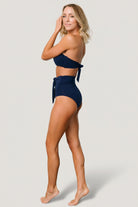 Rear view of navy high-waist bikini bottom showing moderate coverage and back seam shaping for a secure, flattering fit.