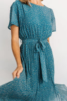 Close-up of Persian blue chiffon fabric and delicate floral print on the Prim Pleated Midi Dress, highlighting pleat texture and lining.
