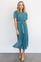 Model movement shot of Prim Pleated Midi Dress in Persian blue print emphasizing flow of pleated chiffon skirt and versatile styling.