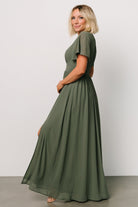 Model walking in the Ramona Maxi Dress dark sage, showing movement of the chiffon skirt and elegant occasion-ready styling.