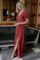 Side view of terracotta Ramona maxi dress on model, emphasizing left leg slit and graceful skirt drape.
