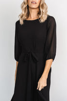 Model wearing Rebecca Maxi Dress in black, full-length pose showing sleeve length, skirt sweep and the dress's elegant silhouette.