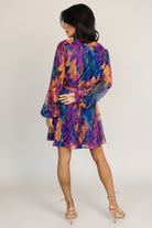 Side view of the Rev pleated mini dress in blue multi, showing adjustable waist tie and soft pleat detail at the skirt.
