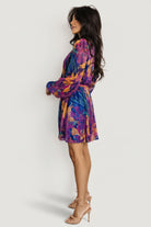 Styled look of the Rev pleated mini dress in blue multi print paired with casual sandals to show everyday resort styling options.