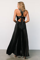 Full-length on-model shot of Aakaa Sandra black pleated maxi dress showing ankle-length skirt and elegant silhouette in motion.