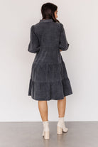 Styled flatlay of washed black babydoll mini emphasizing button-down front, side pockets, and tiered skirt for casual, travel-ready styling.