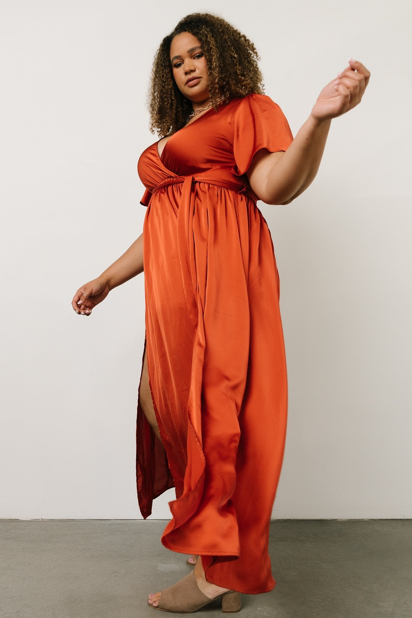 Full-length seated pose wearing the rust maxi dress to illustrate skirt fall, partial lining length and overall fit on a model.