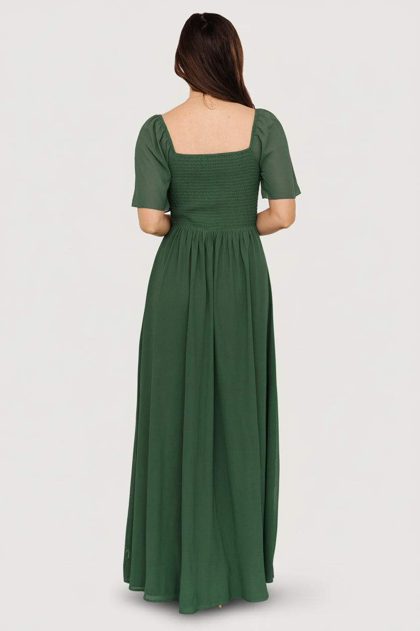 Model walking in Sierra Sweetheart Maxi Dress in evergreen, showing chiffon flow, front slit, and event-ready silhouette.