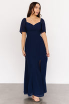 Full-length image of navy chiffon maxi dress on model, illustrating flow, length, and front-left slit for movement.