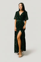 Back and side view of dark green Uma Velvet Maxi Dress revealing full skirt, lining finish, and the placement of the leg slit.