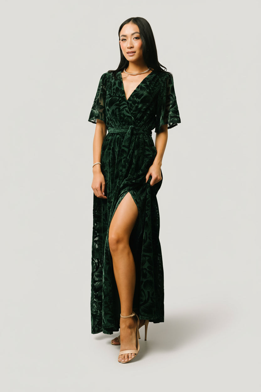 Back and side view of dark green Uma Velvet Maxi Dress revealing full skirt, lining finish, and the placement of the leg slit.