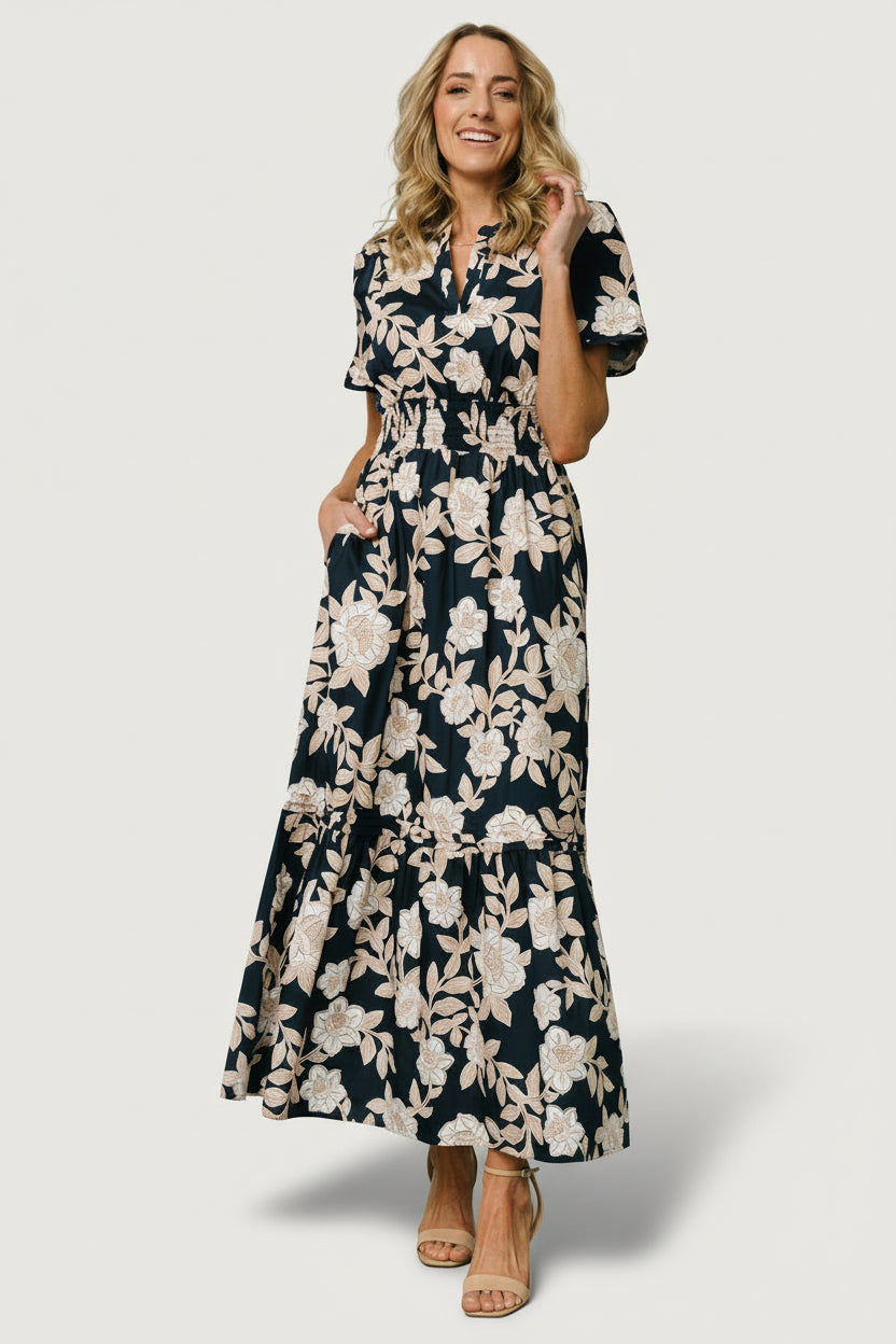 Front view of Vera Maxi Dress in navy floral on model — notched V-neck, smocked waistband, tiered skirt and handy side pockets for effortless style.