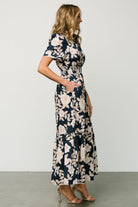 Back view of Vera Maxi Dress in navy floral highlighting subtle layered back detail, smocked waistband and the full maxi silhouette on model.