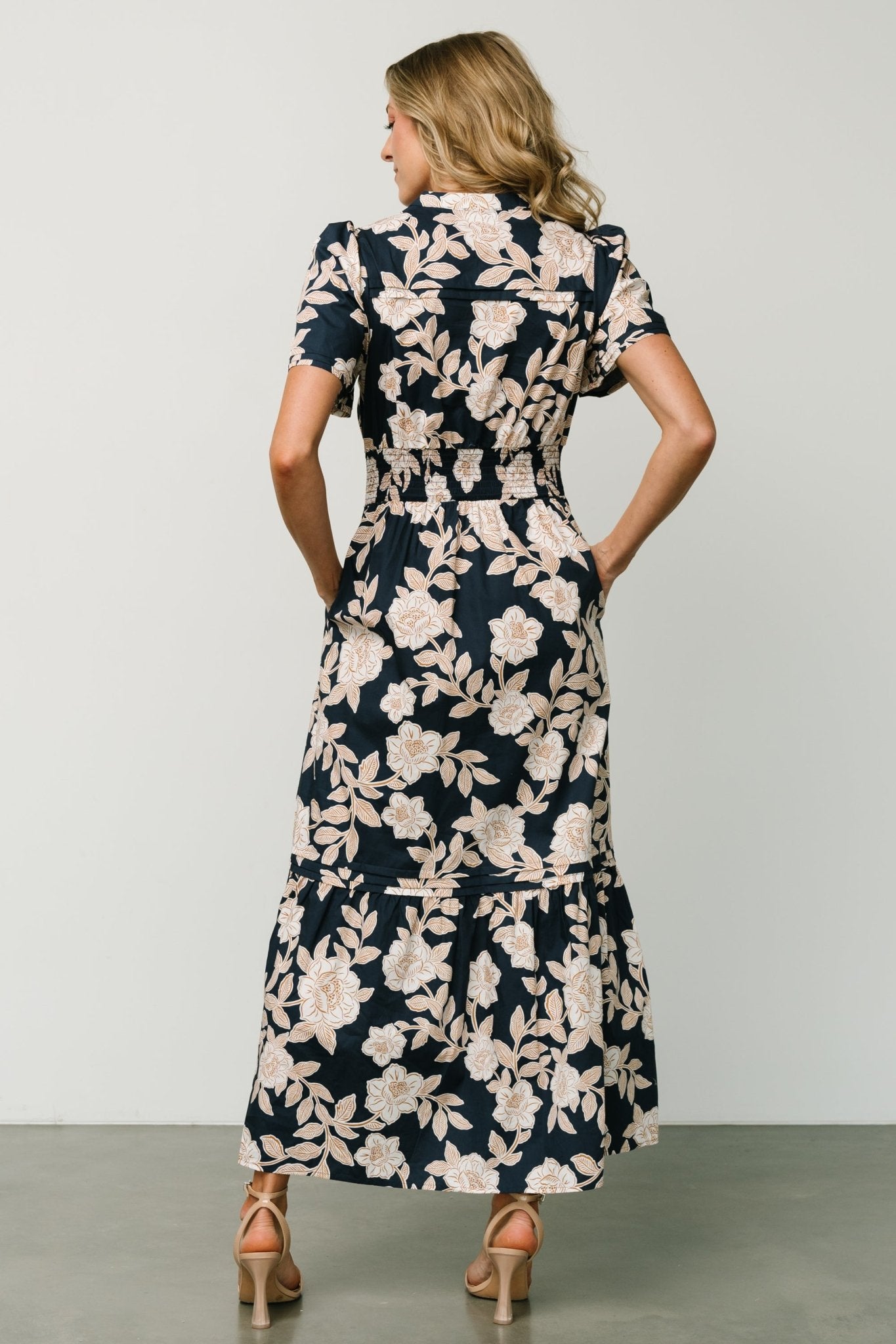 Full-length view of Vera Maxi Dress in navy floral styled with sandals, showing movement of the tiered skirt and overall fit on model.